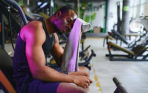 African American man sitting on gym equipment too tired to finish his workout