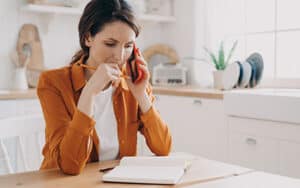 Middle aged woman sitting at kitchen table waiting to talk to her doctor on the phone