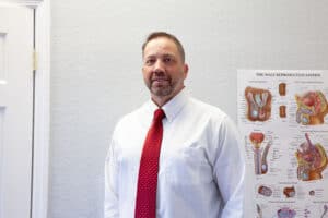 Michael Durham MS MSRN APRN Age Well NP standing near medical diagram